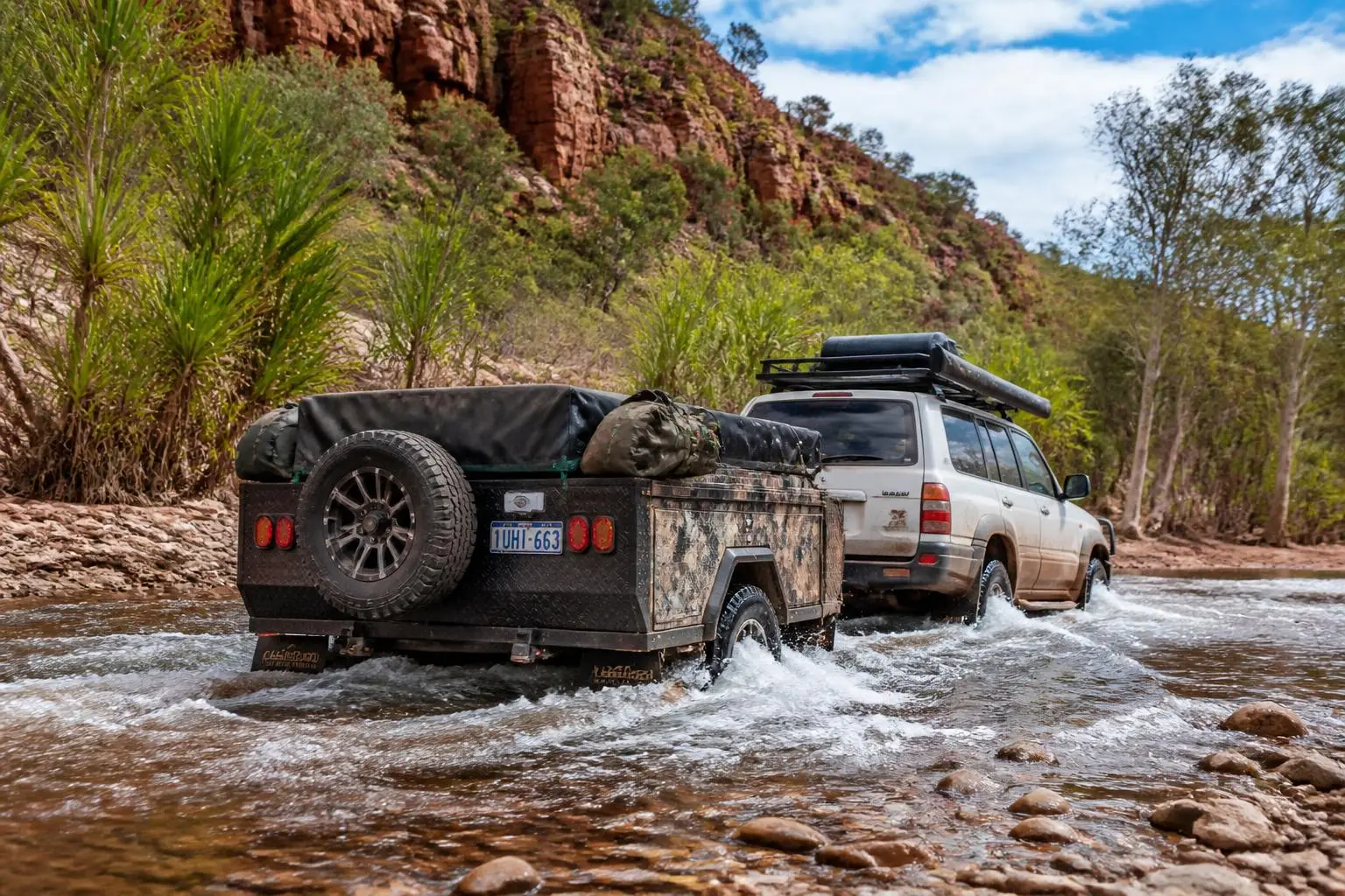 Off-road camper trailer crossing a rocky river in the Australian outback
